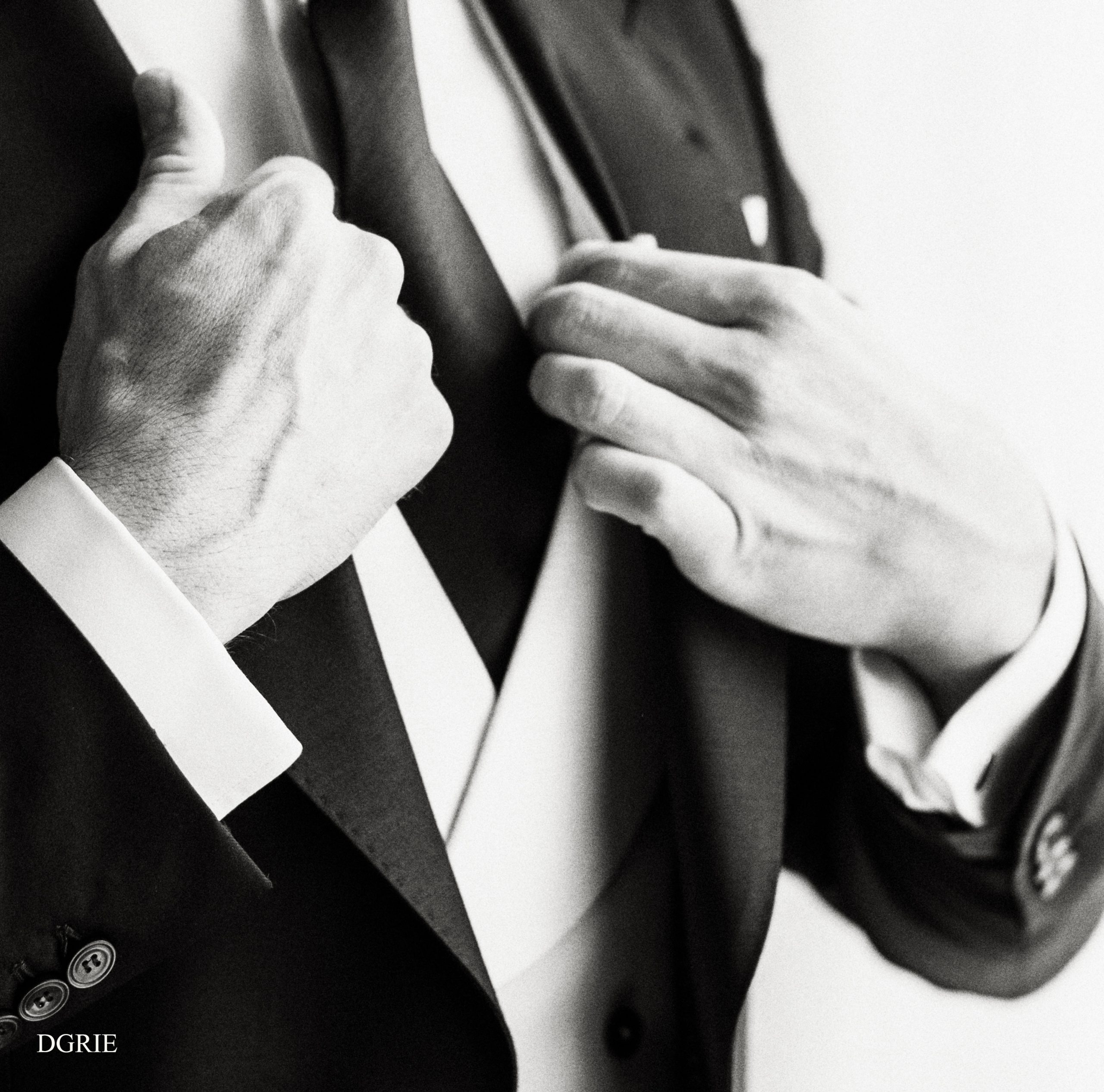 man-black-tuxedo-adjusts-his-tie ตัดสูทแต่งงาน สูทเจ้าบ่าว The Best Groom Tuxedo